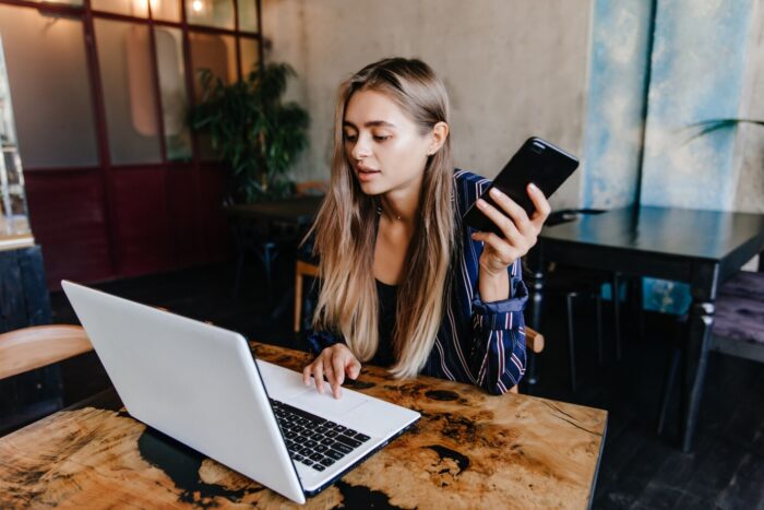 Zena koja radi preko laptopa i prica na telefon