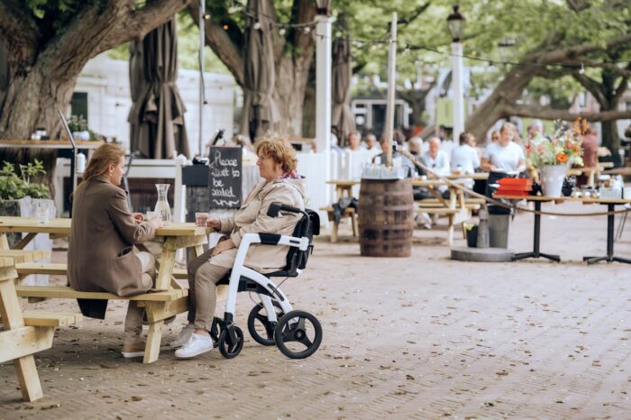 Osoba u kolicima sedi u drustvu u basti restorana.