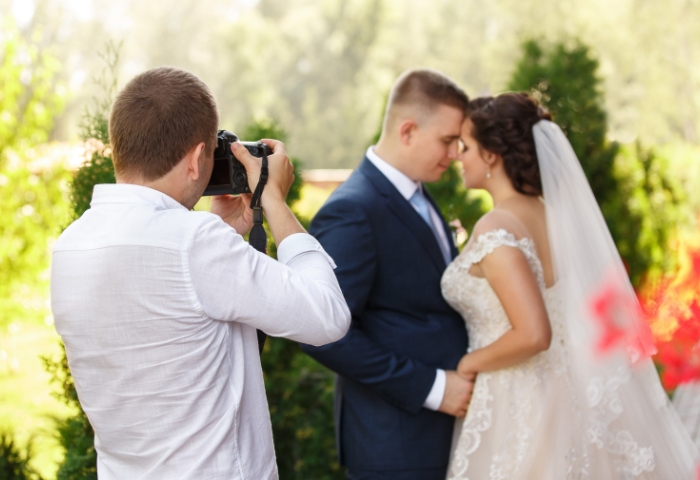 Fotograf slika mladi par u venčanici i odelu tokom svadbenog dana na otvorenom